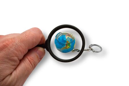 Earth is in magnifying glass which holds handの写真素材
