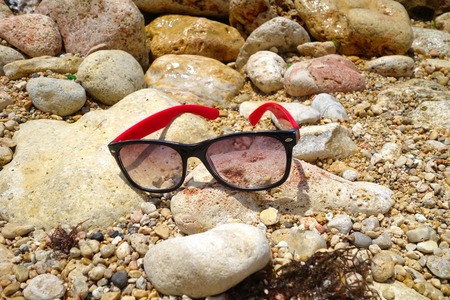 sun glasses on the stone near the seaの写真素材