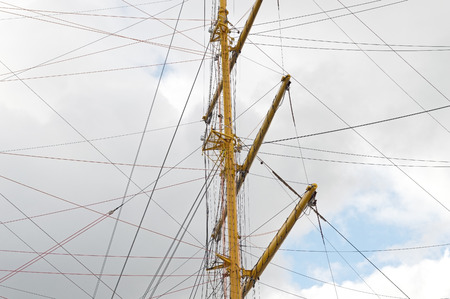 Masts and rigging of a sailing ship against blue sky and clouds
