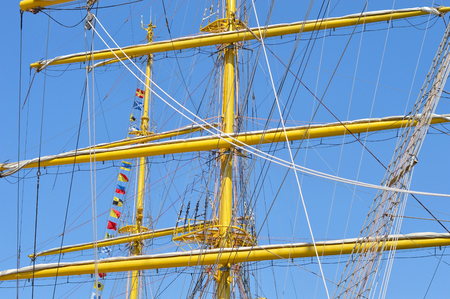 Masts and rigging of a sailing ship against blue sky and clouds