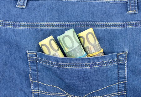Roll of euro banknotes in a blue jeans pocketの写真素材