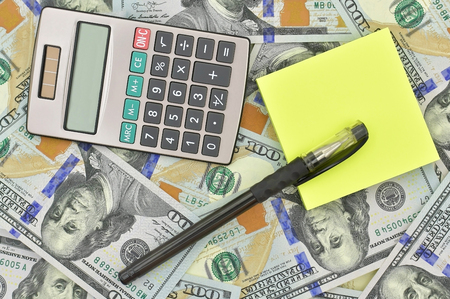 Calculator, pen, note paper and U.S. dollars isolated on a white backgroundの写真素材