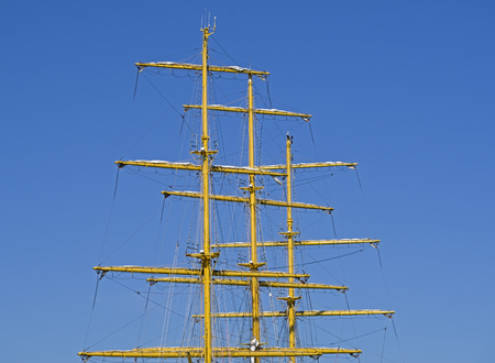 Masts and rigging of a sailing ship against blue sky and clouds