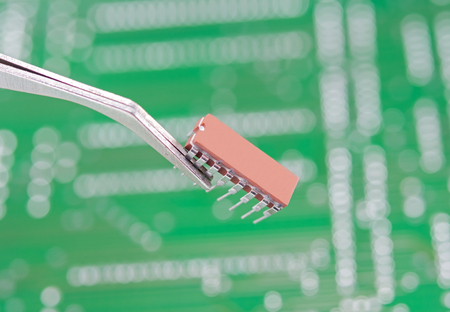microchip with tweezers on background Green circuit board