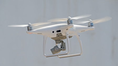 Flying drone quadcopter in front of white building
