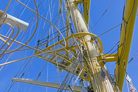 Masts and rigging of a sailing ship against blue sky and clouds