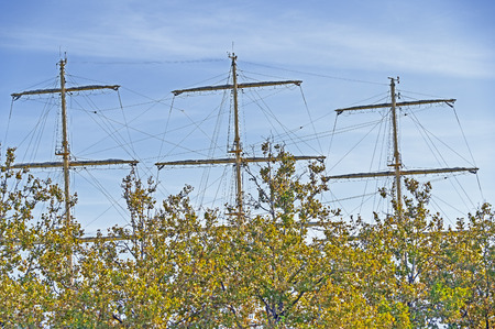 Masts and rigging of a sailing ship against blue sky and clouds