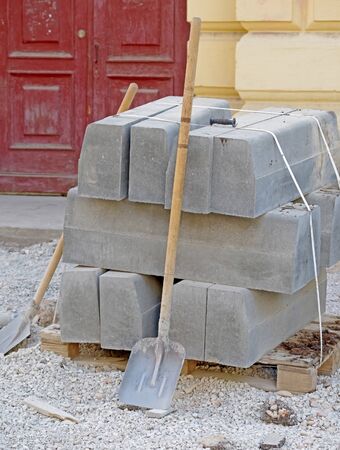 The pallet with a stack of concrete curbstone and shovelsの写真素材
