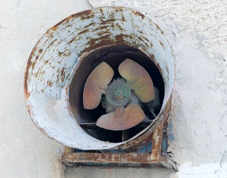 Old dirty grungy abandoned rusty fan on the factory wallの写真素材
