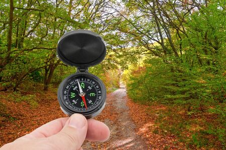 hand with compass on background autumn forest