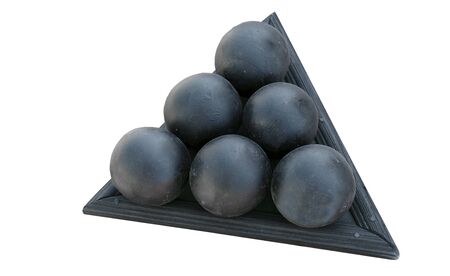 A pyramid of black cannonballs on a white backgroundの写真素材