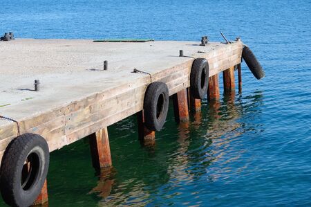 car tire with a metal chain on a old concrete sea pierの写真素材
