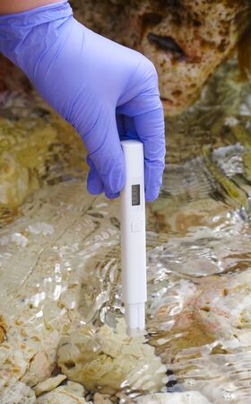 A researcher uses a water tester to test the TDS content of a water body