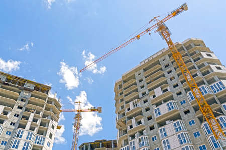 Building crane and building under construction against evening blue sky