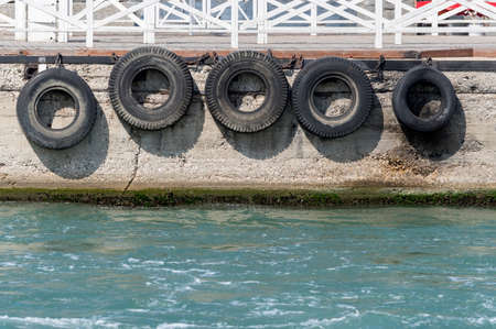 car tire with a metal chain on a old concrete sea pierの写真素材