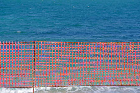 orange grid of barrier tape near the sea