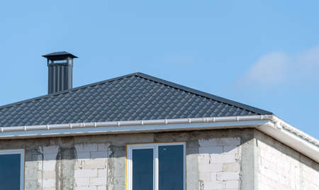 metal pipes on the roof of a small house on background of blue sky