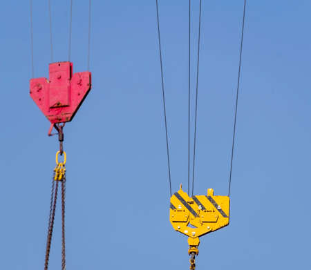 Crane hook hanging on steel ropes on background of blue sky