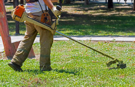 a man mows the grass with a gas mower