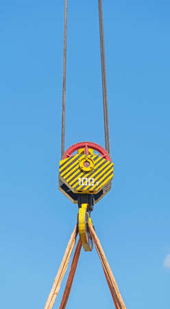 Crane hook hanging on steel ropes on background of blue skyの写真素材