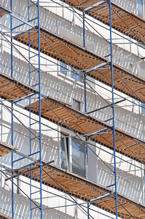 scaffolding on the facade of a house under construction on a background blue skyの写真素材