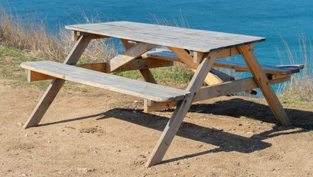 homemade wooden table with benches near the blue sea