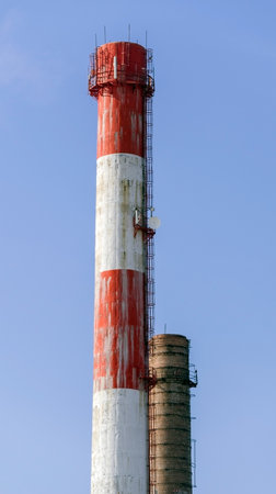Red and white old brick industrial pipe against the blue skyの写真素材