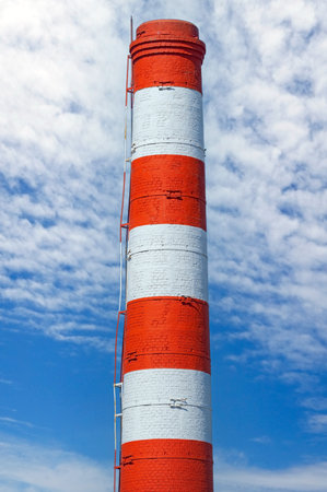 Red and white old brick industrial pipe against the blue sky