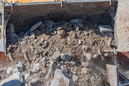 Excavator bucket filled with soil, stones and pieces of concreteの写真素材