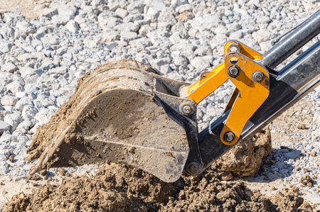 Excavator bucket filled with soil, stones and pieces of concrete