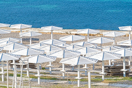 Sea beach with sand and long row of wooden umbrellasの写真素材