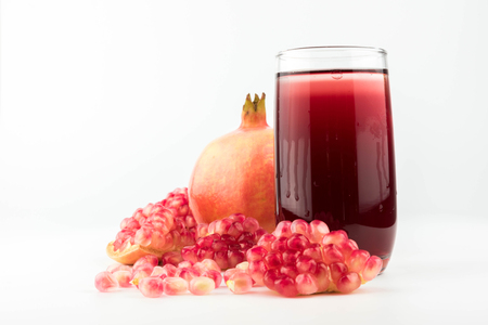 Glass of pomegranate juice with fruit isolated on white.の写真素材