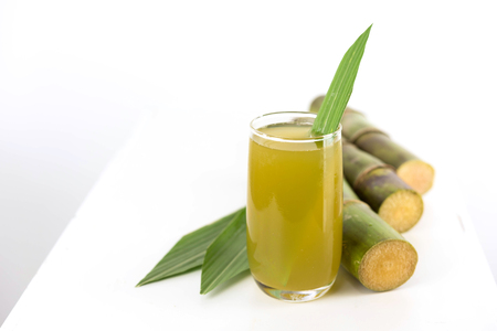 Fresh sugar cane juice in glass on table white backgroundの写真素材