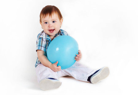 Child sitting with blue baloon and hugs itの写真素材