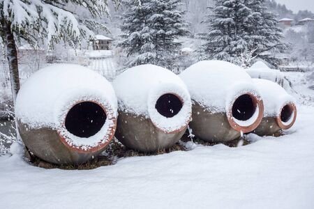 Snow covered georgian jugs for wine, outdoor in winter.の写真素材