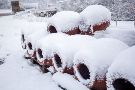 Snow covered georgian jugs for wine, outdoor in winter.