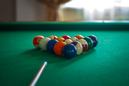 Billiard balls on green table with billiard cue