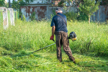 The gardener cutting grass by lawn mower.