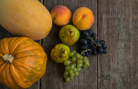 Melon, grapes, peach, Pear and pumpkin on old wooden tableの写真素材