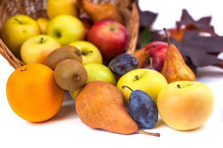 apples and other fruits in a wicker basket on a white background.