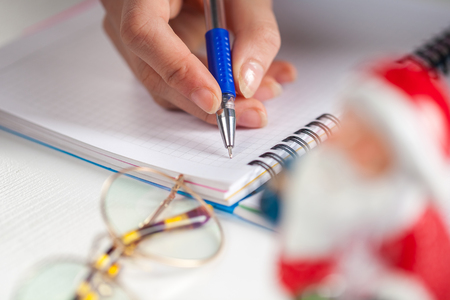 Hands with a pen, notebook and an envelop for letter. A girl is ready to write a letter to Santa Claus. dreams come true, magic holidays and merry Christmas, gifts timeの写真素材