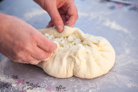 Baker hands preparing khachapuri on kitchen table. View on cook making traditional georgian treat...