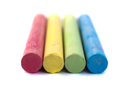 Colored chalks on white background with soft shadows.