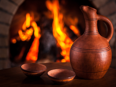 Georgian clay pottery against cozy fireplace background, winter vacation, in country house.の写真素材