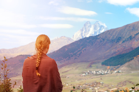 beautiful blonde girl on the background of Mount Ushba, mountains of Svaneti, Georgia.
