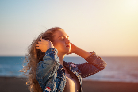 Beautiful woman on the beach enjoying fresh air freedom on sunset.の写真素材