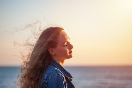 Beautiful woman on the beach enjoying fresh air freedom on sunset.の写真素材