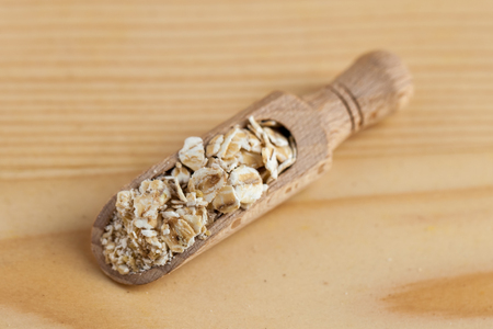 Oat flakes in a wooden bowl with a scoop on the wooden board.の写真素材
