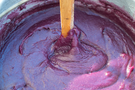 Cooking grape juice, corn and white flour in big pot boiler mixing with wooden spoon for pelamushi, tatara or churchkhela - traditional Georgian dessert sweets with walnuts or hazelnuts.の写真素材