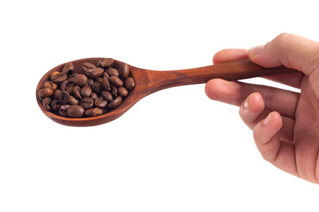 Roasted coffee beans on a wooden spoon in a womans hand on a white background.の写真素材